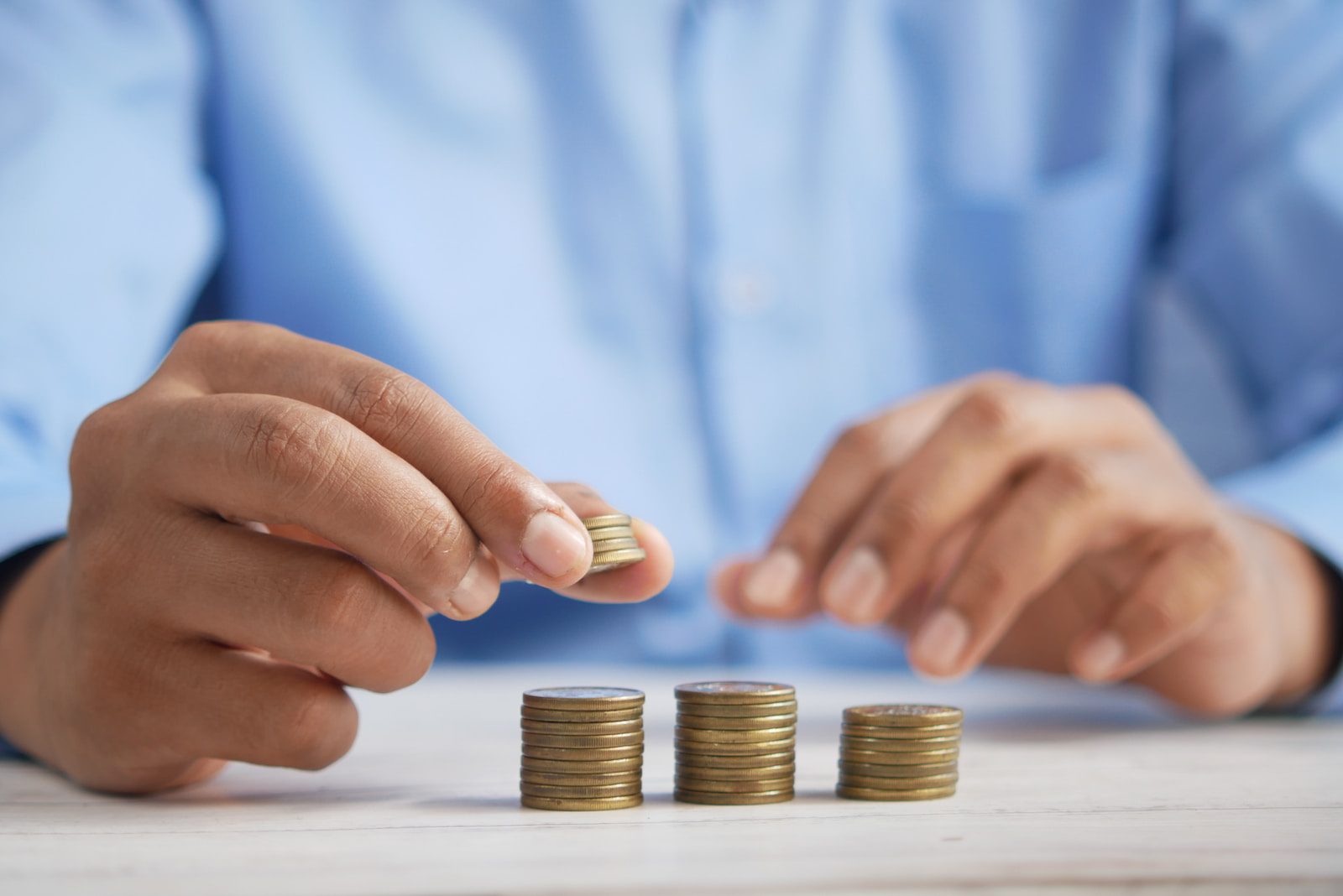 A person stacking coins on top of a table